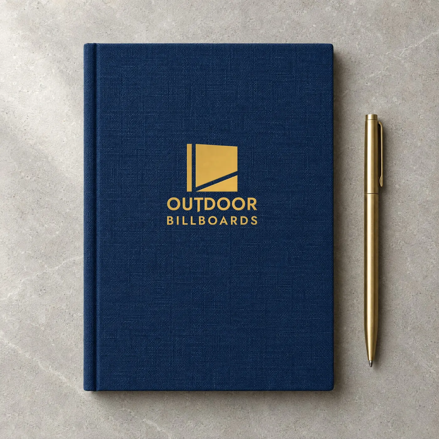 Navy linen notebook with a gold foil Outdoor Billboards logo and a brass pen